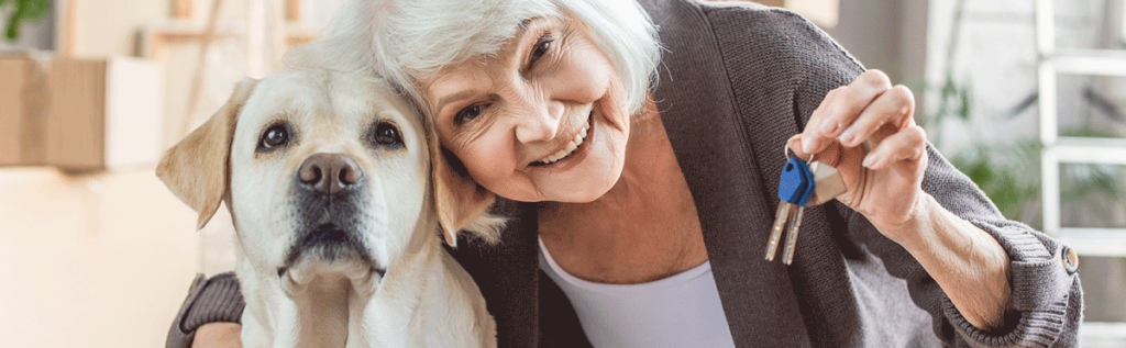 Elderly woman holding keys and embracing her yellow lab trained service dog